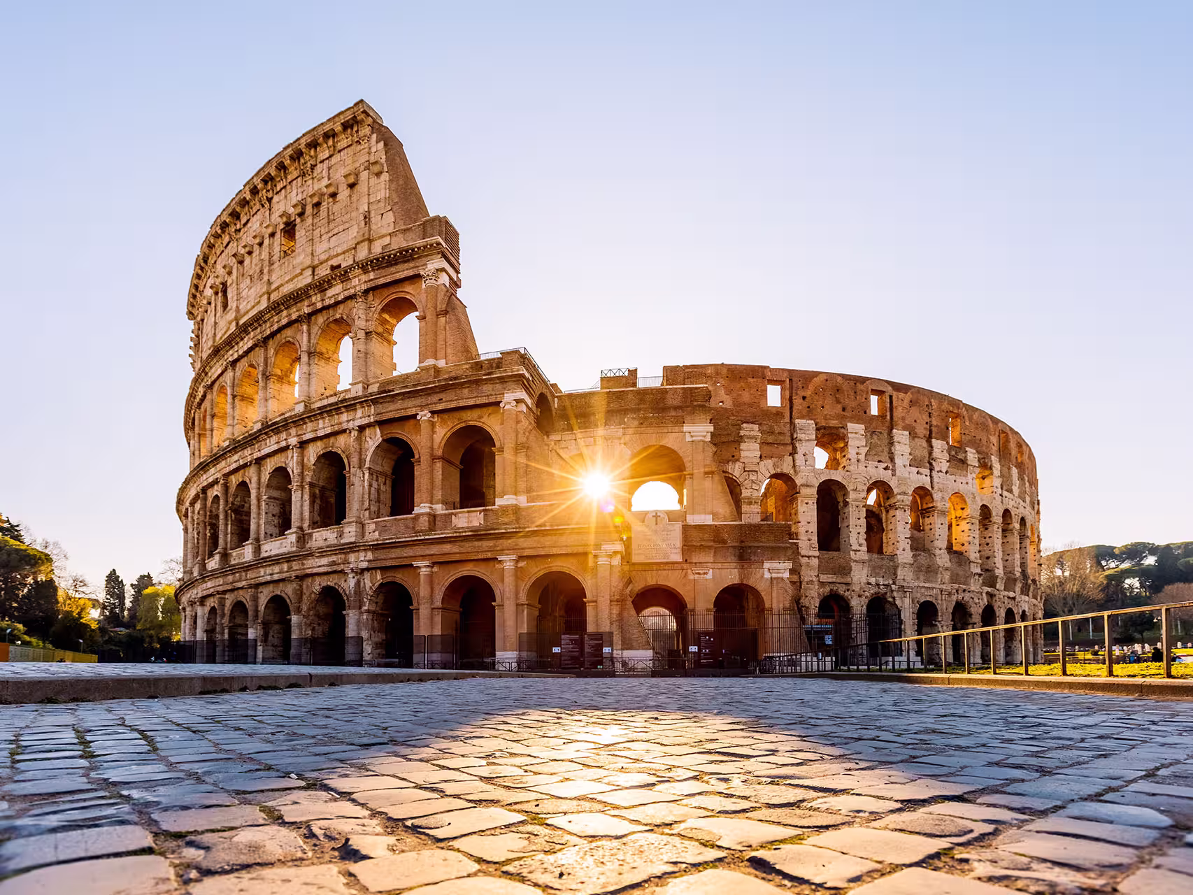 The Colosseum in Rome at sunrise with sunlight through the arches