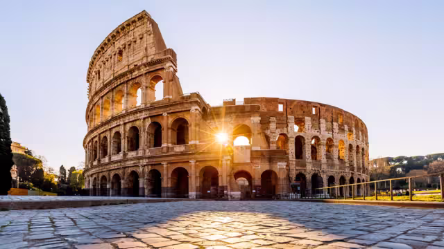 The Colosseum in Rome at sunrise with sunlight through the arches