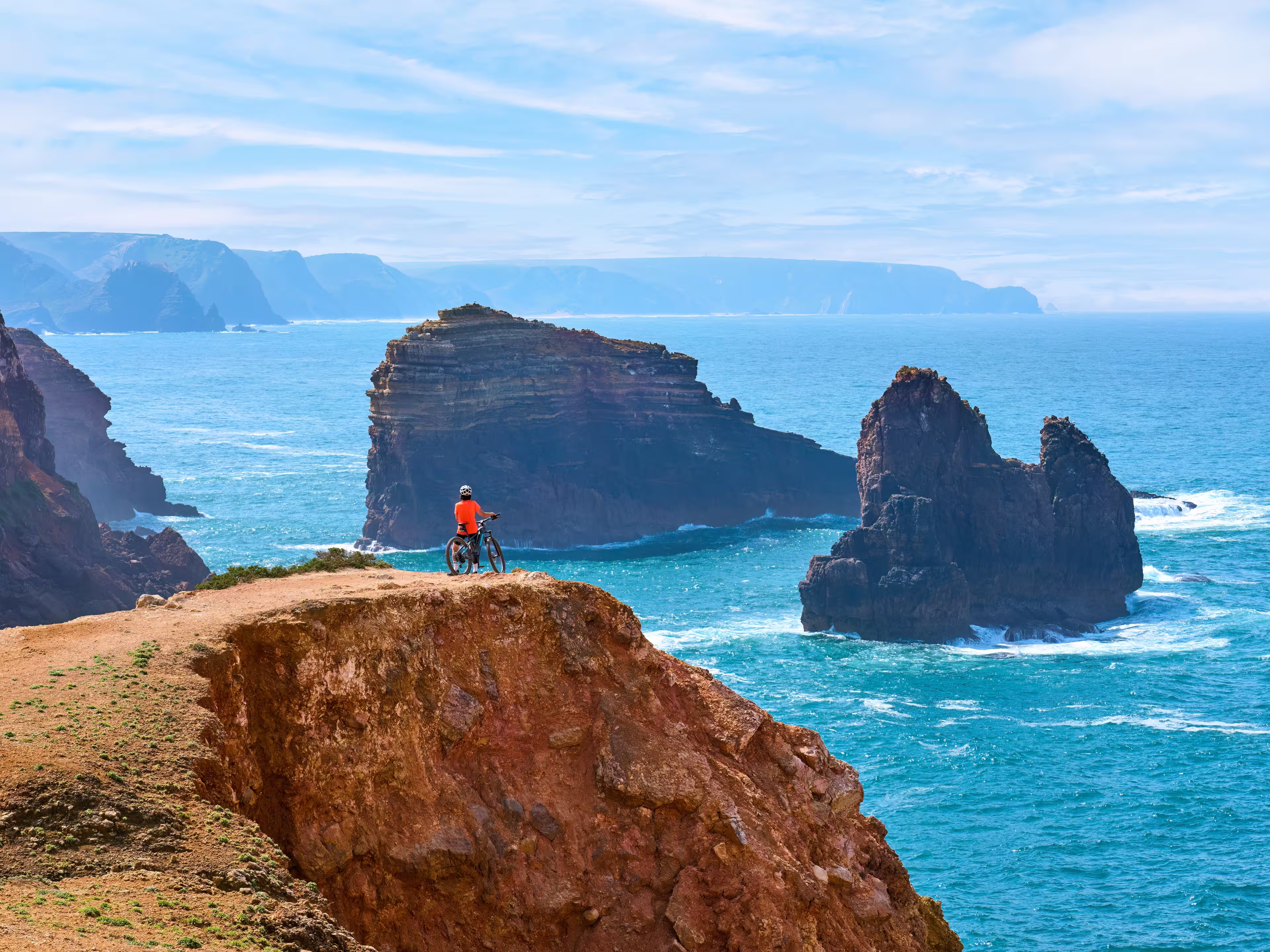 happy active senior woman cycling on the the rocky cliffs of the Vicentina coast of  Portugal near Sagres and Vila do Bispo