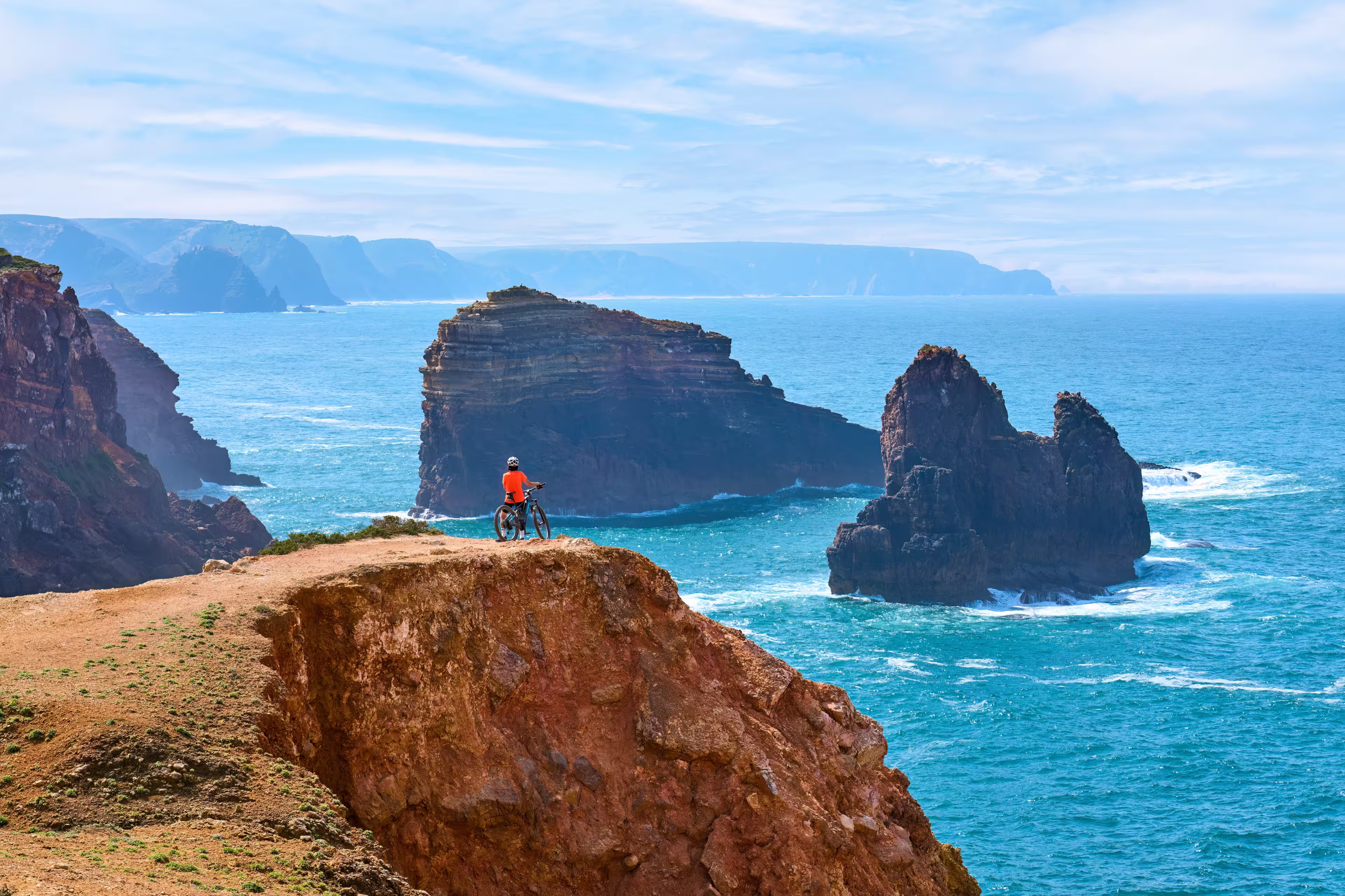 happy active senior woman cycling on the the rocky cliffs of the Vicentina coast of  Portugal near Sagres and Vila do Bispo