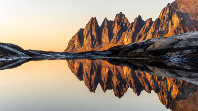 A scenic view of Devils teeth mountains in Senja, Norway, at bright sunset