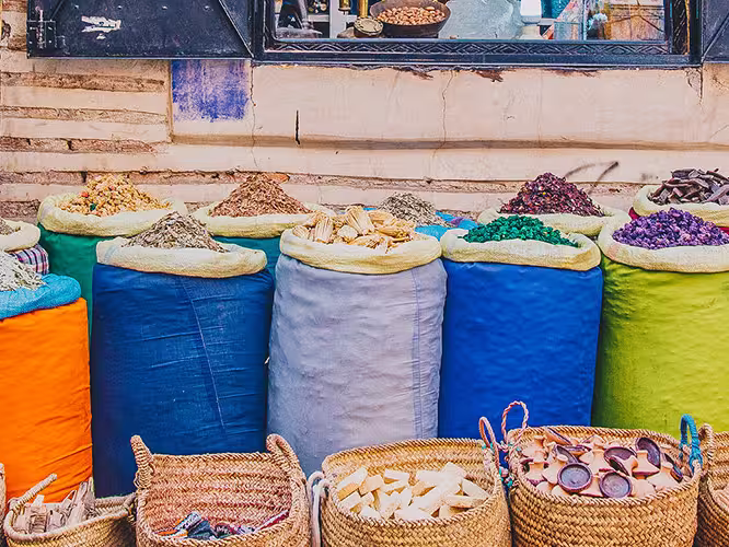 Local man sits at colouful spice market, Marrakech, Morocco
