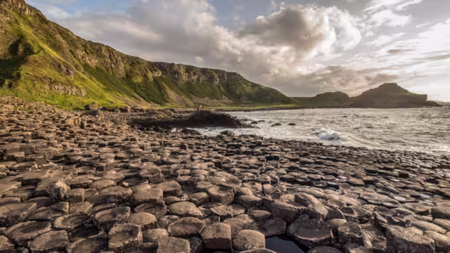Travellers in the distance explore the Giants Causeway on the northern shore of Ireland