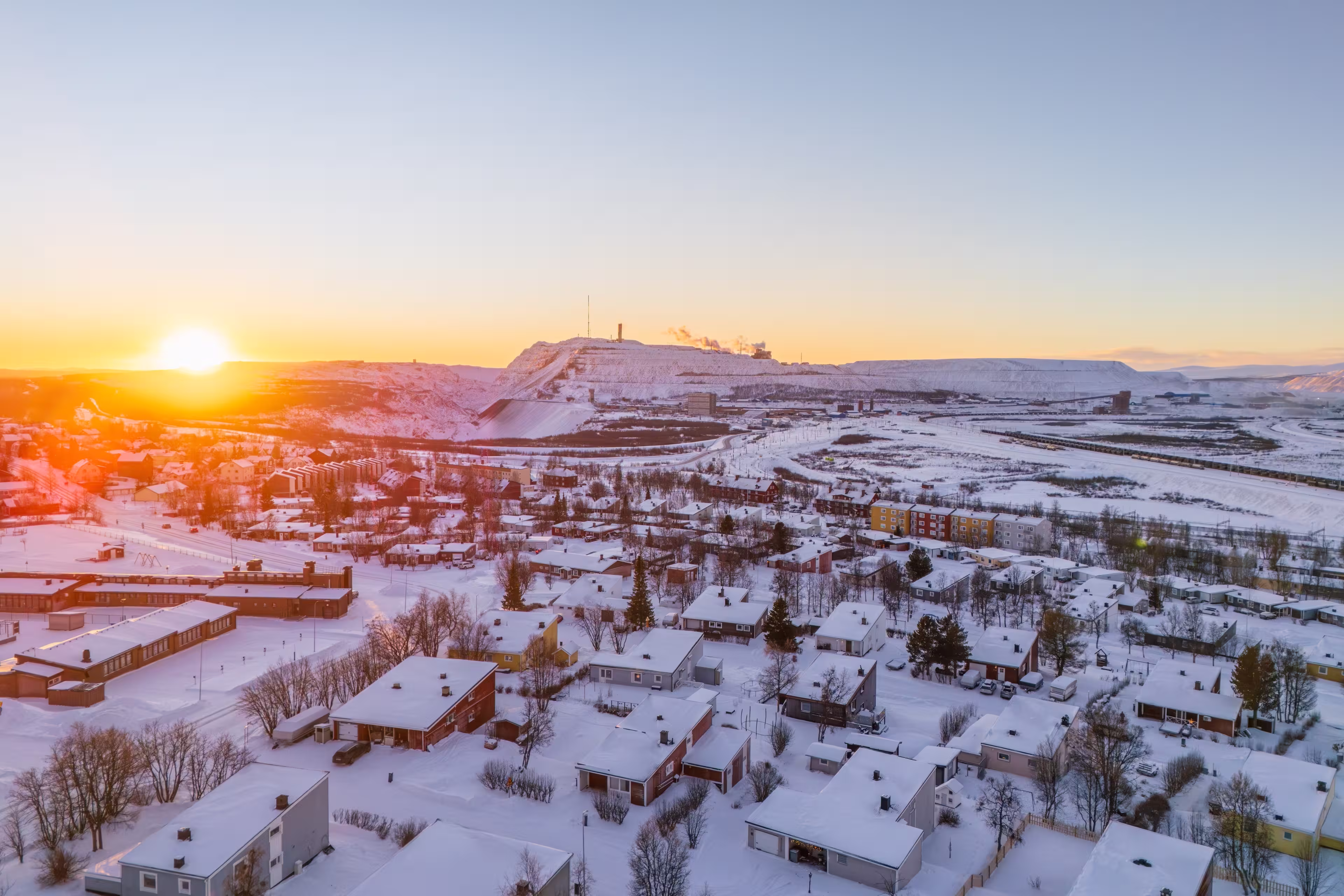 Kiruna and the iron ore mine, Sweden, at high noon during the arctic winter, snow, colorful houses, sun just above the horizon
