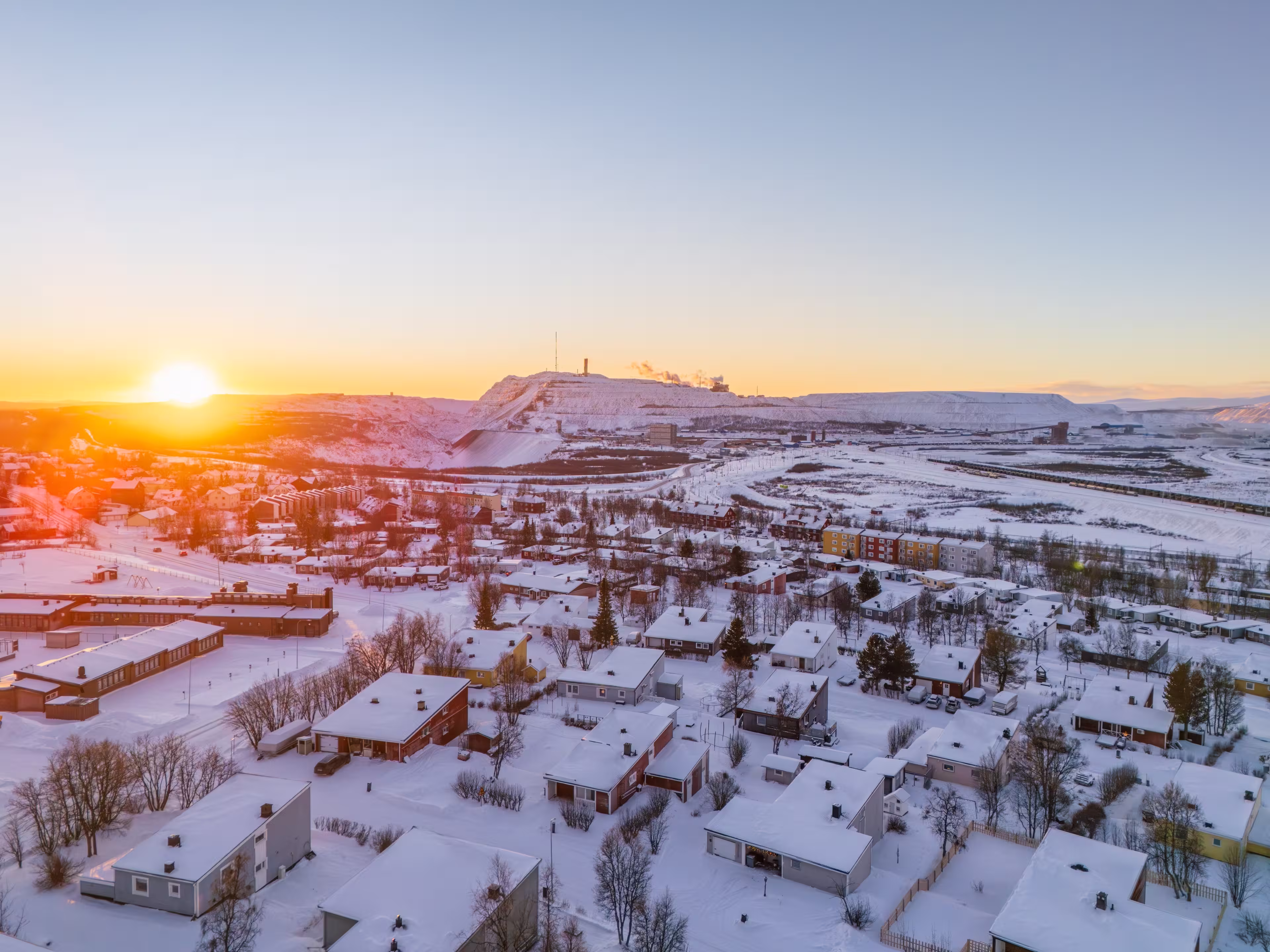Kiruna and the iron ore mine, Sweden, at high noon during the arctic winter, snow, colorful houses, sun just above the horizon