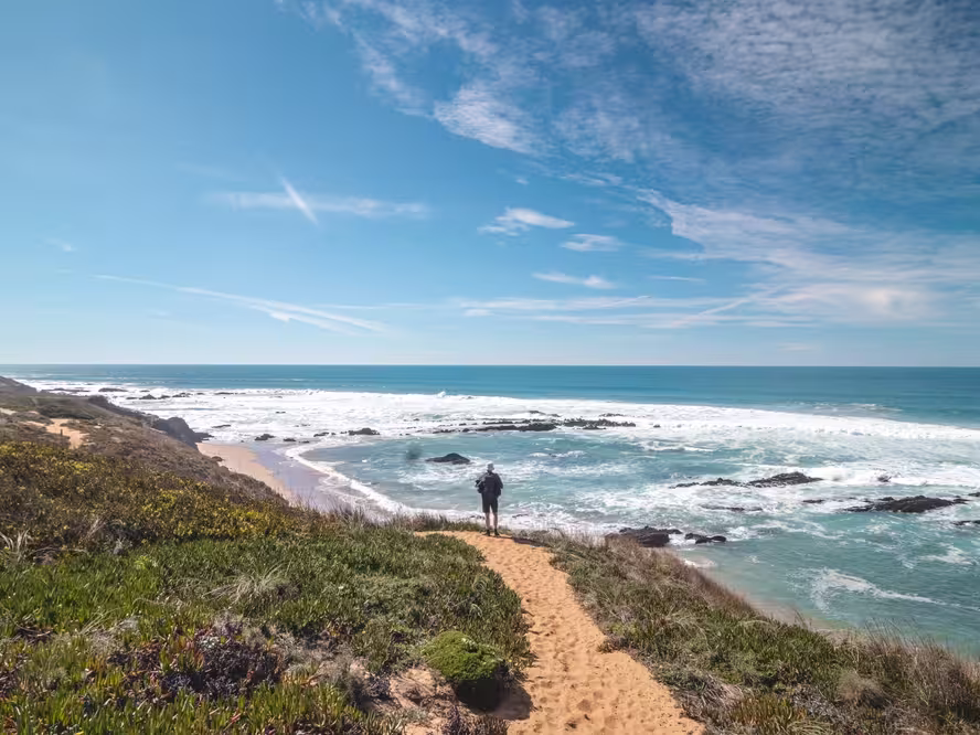 Traveler walks on a sandy path during a sunny day in Odemira region, western Portugal. Wandering along the Fisherman Trail, Rota Vicentina.