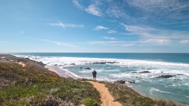 Traveler walks on a sandy path during a sunny day in Odemira region, western Portugal. Wandering along the Fisherman Trail, Rota Vicentina.