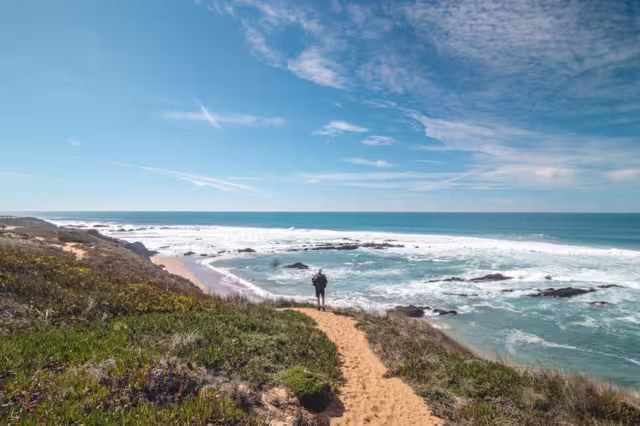 Traveler walks on a sandy path during a sunny day in Odemira region, western Portugal. Wandering along the Fisherman Trail, Rota Vicentina.