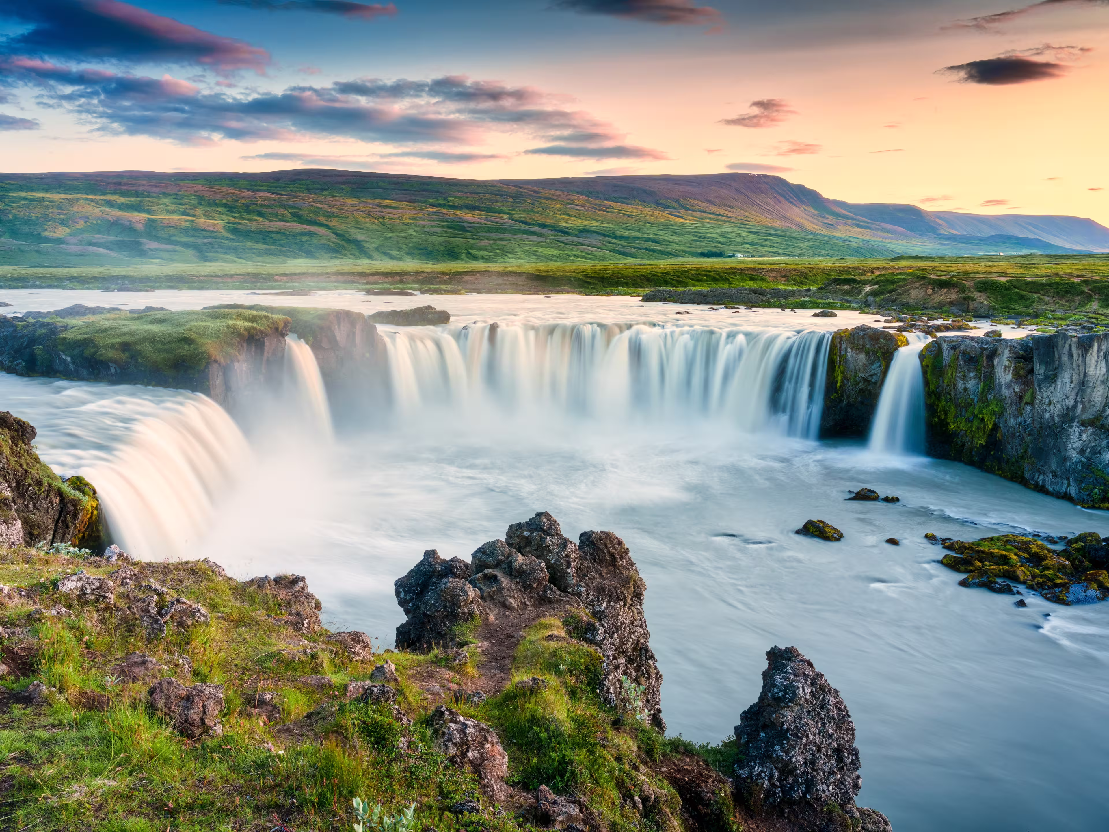 Majestic landscape of Godafoss waterfall or waterfall of the gods flowing and colorful sunset sky on Skjalfandafljot river in summer at Northern Iceland