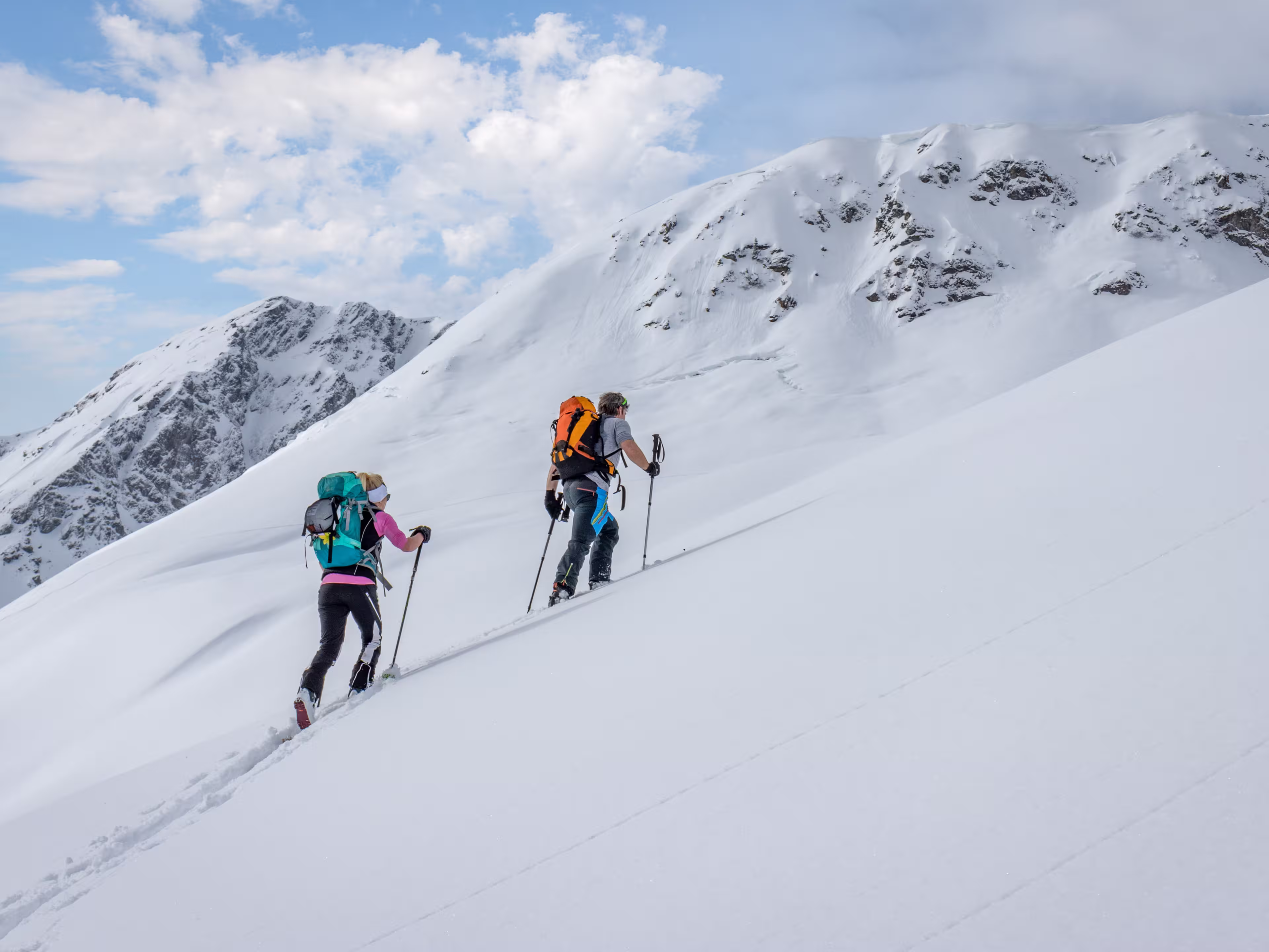 Ski touring couple hiking up a summit in the alps