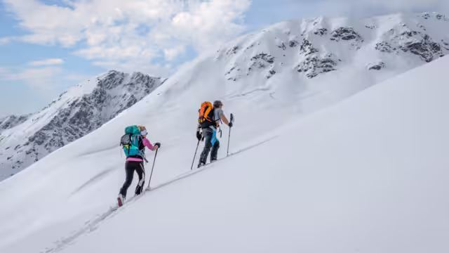 Ski touring couple hiking up a summit in the alps