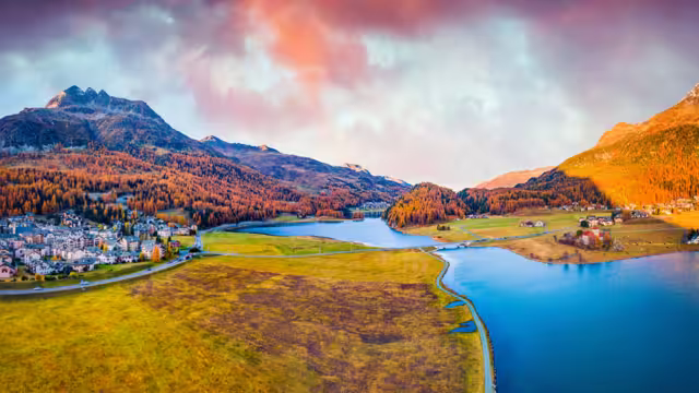 View from flying drone. Amazing autumn scene of Silvaplana village, Maloja Region. Aerial morning view of Swiss Alps. Spectacular evening landscape of Silvaplanersee lake. Traveling concept background