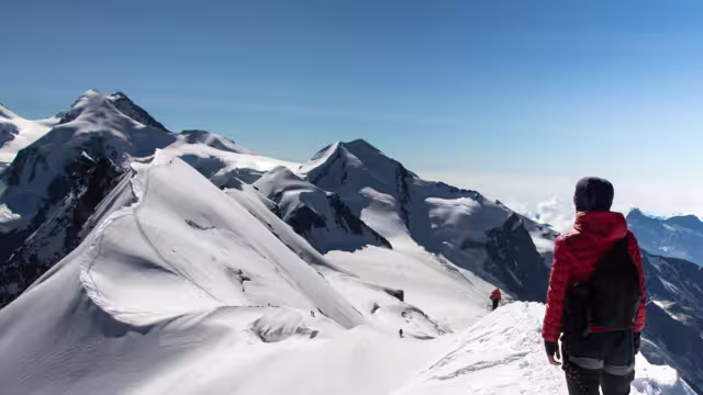 Hiker woman on top of Breithorn mountain, 4164 m above sea level. Zermatt, Pennine Alps, Switzerland, Europe.