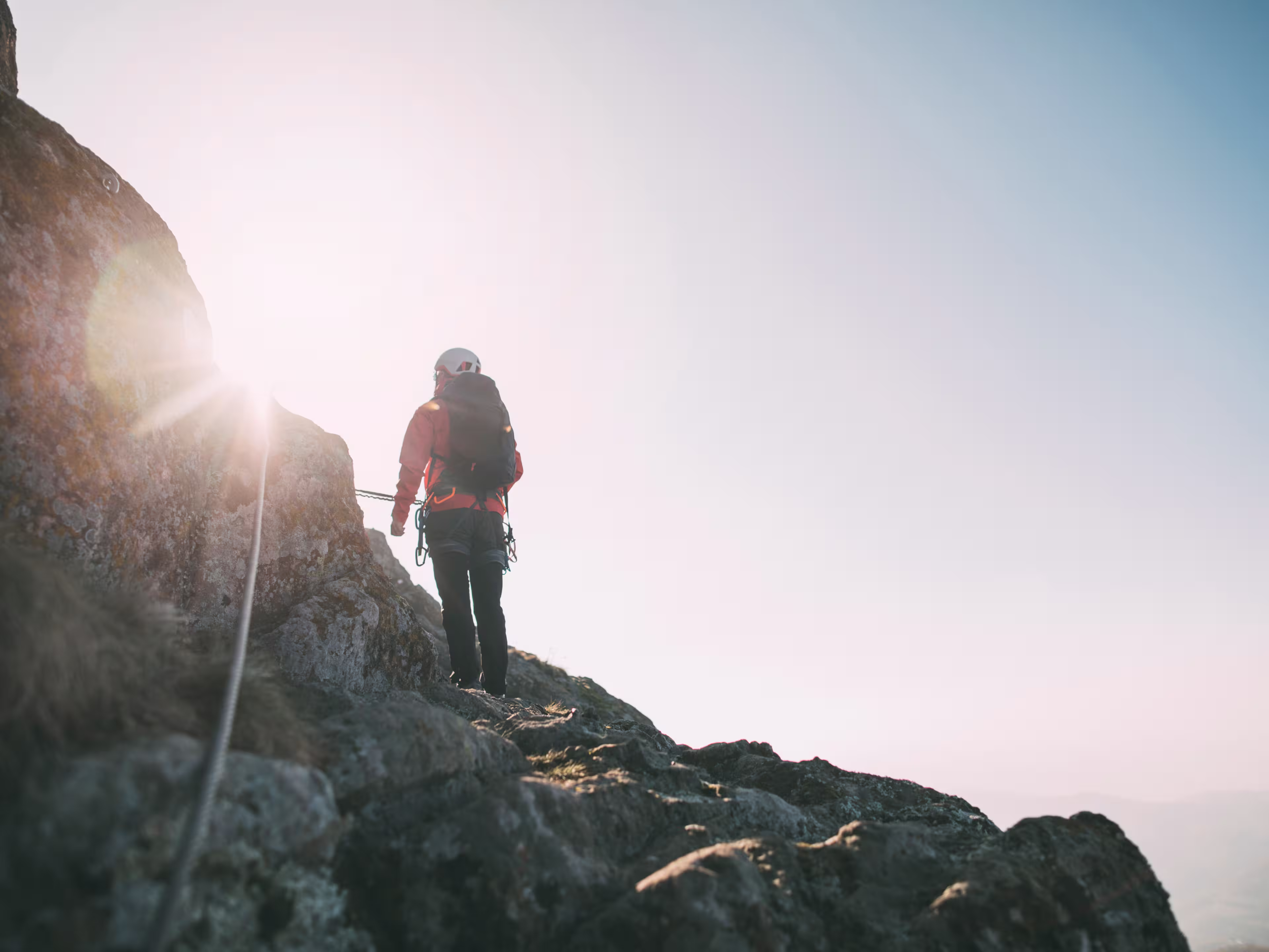 Mountaineer with backpack climbing along a via ferrata