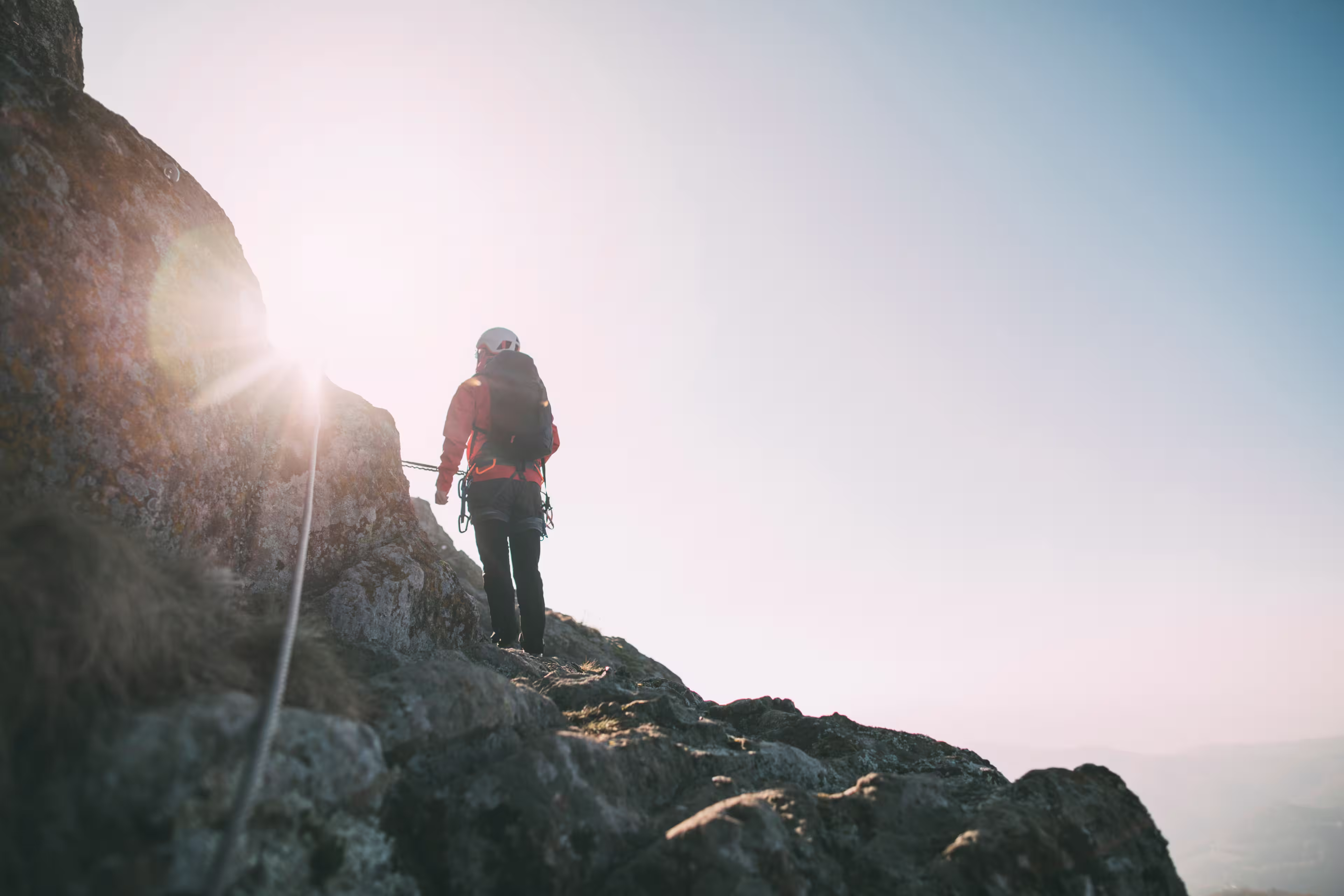 Mountaineer with backpack climbing along a via ferrata