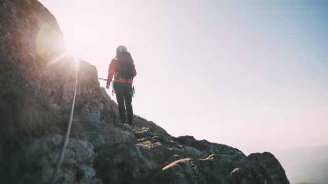 Mountaineer with backpack climbing along a via ferrata