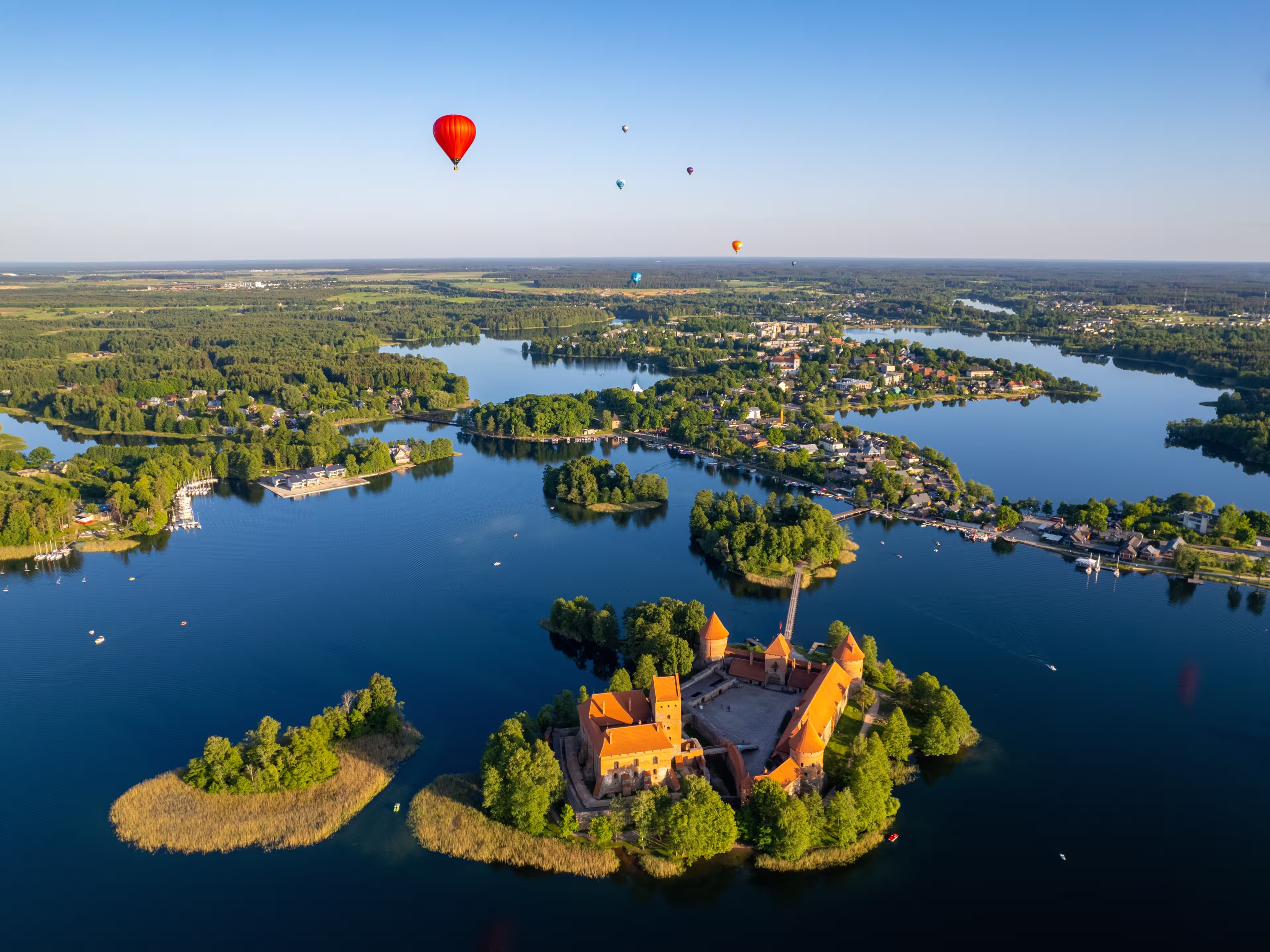 Aerial summer sunny sunset view of Trakai Island Castle and hot air balloons, Lithuania