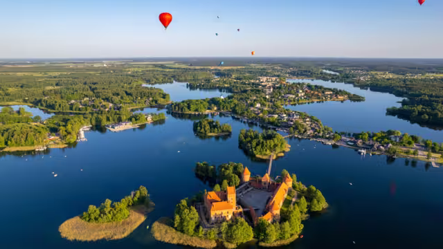 Aerial summer sunny sunset view of Trakai Island Castle and hot air balloons, Lithuania