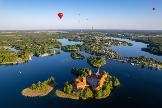 Aerial summer sunny sunset view of Trakai Island Castle and hot air balloons, Lithuania