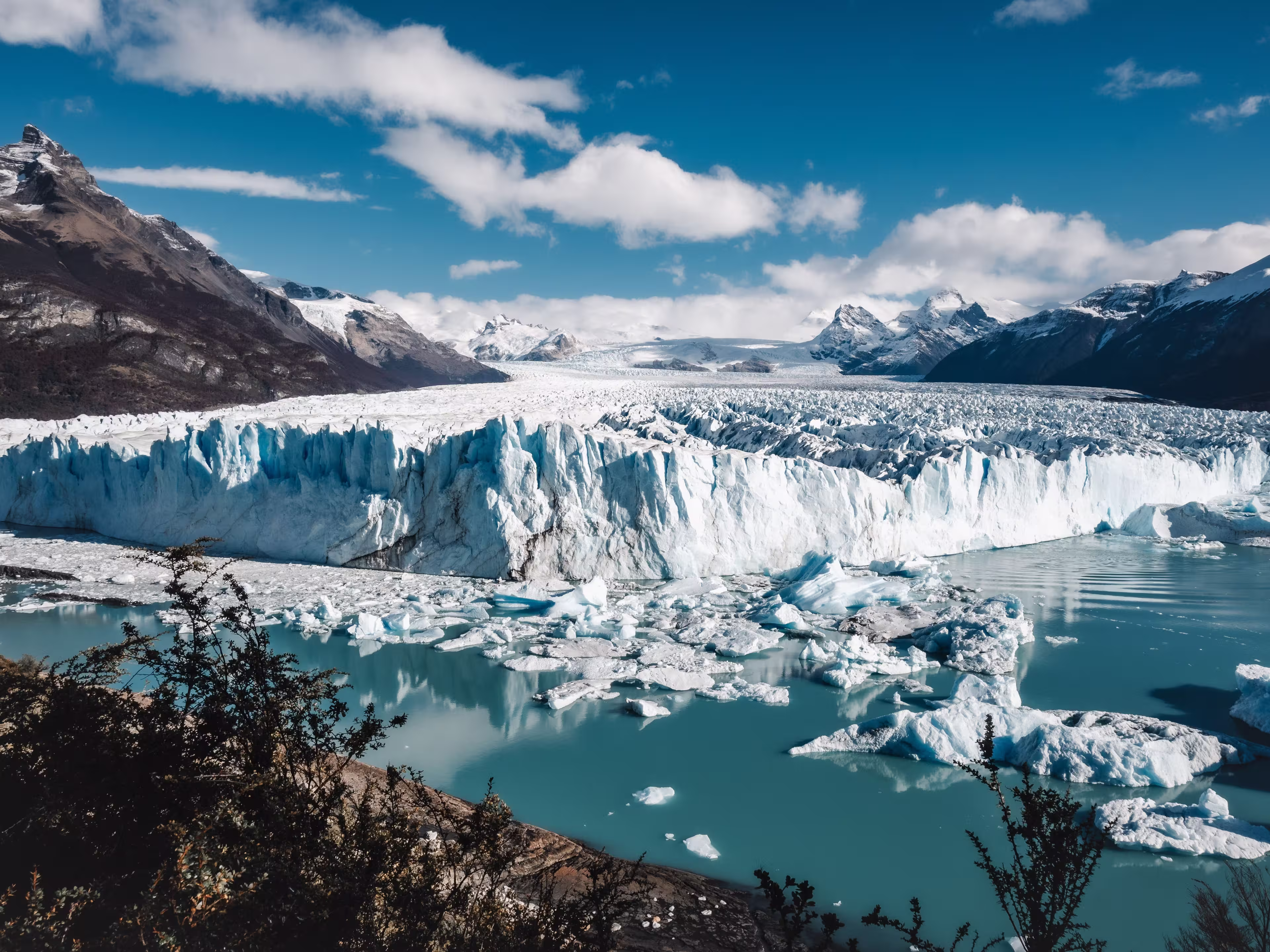 An aerial view of icebergs and glaciers in the water near snowy mountains in El Calafate, Argentina