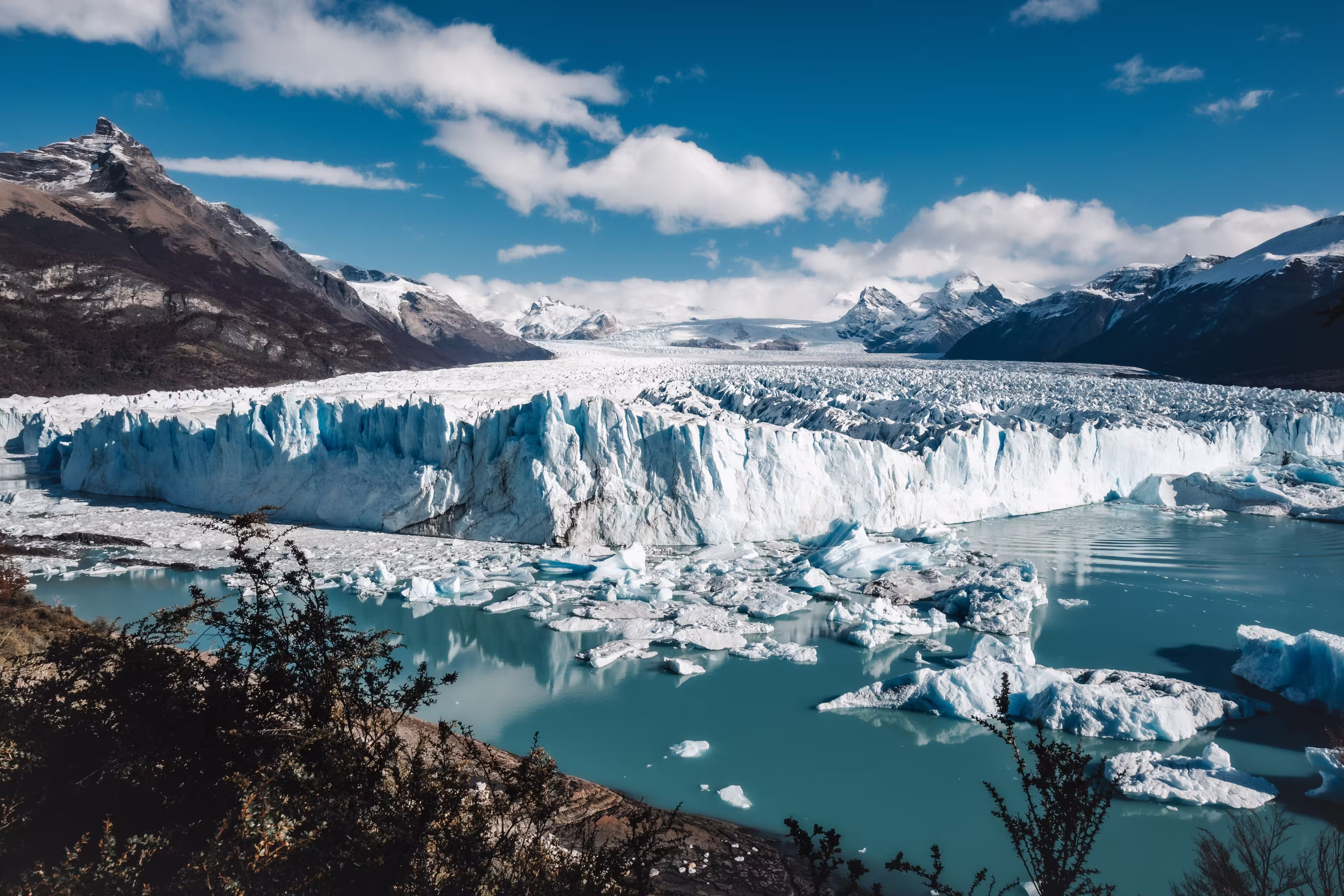 An aerial view of icebergs and glaciers in the water near snowy mountains in El Calafate, Argentina
