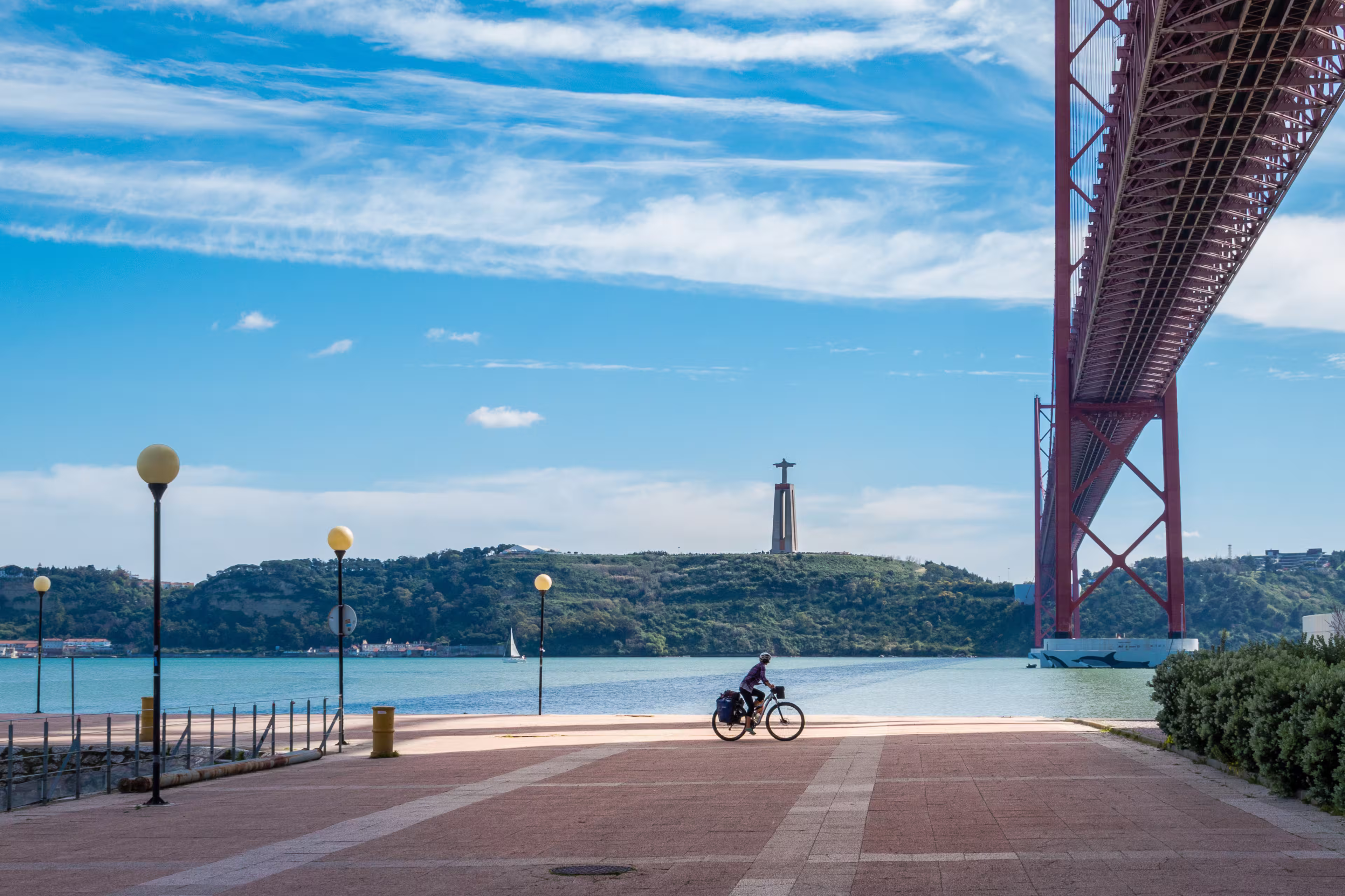 Cyclotourist rides under the April 25 bridge, in Lisbon, Portugal.