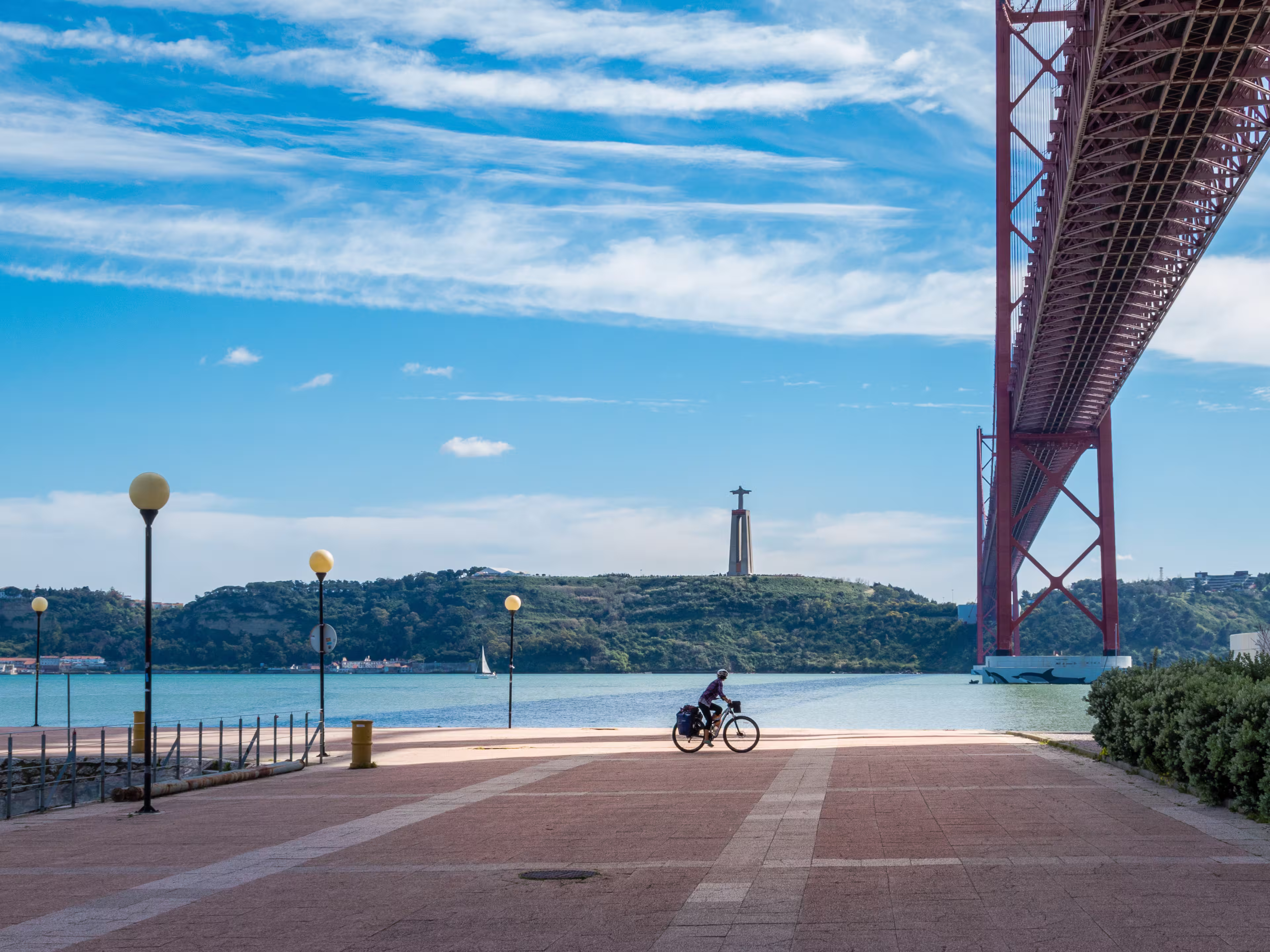 Cyclotourist rides under the April 25 bridge, in Lisbon, Portugal.
