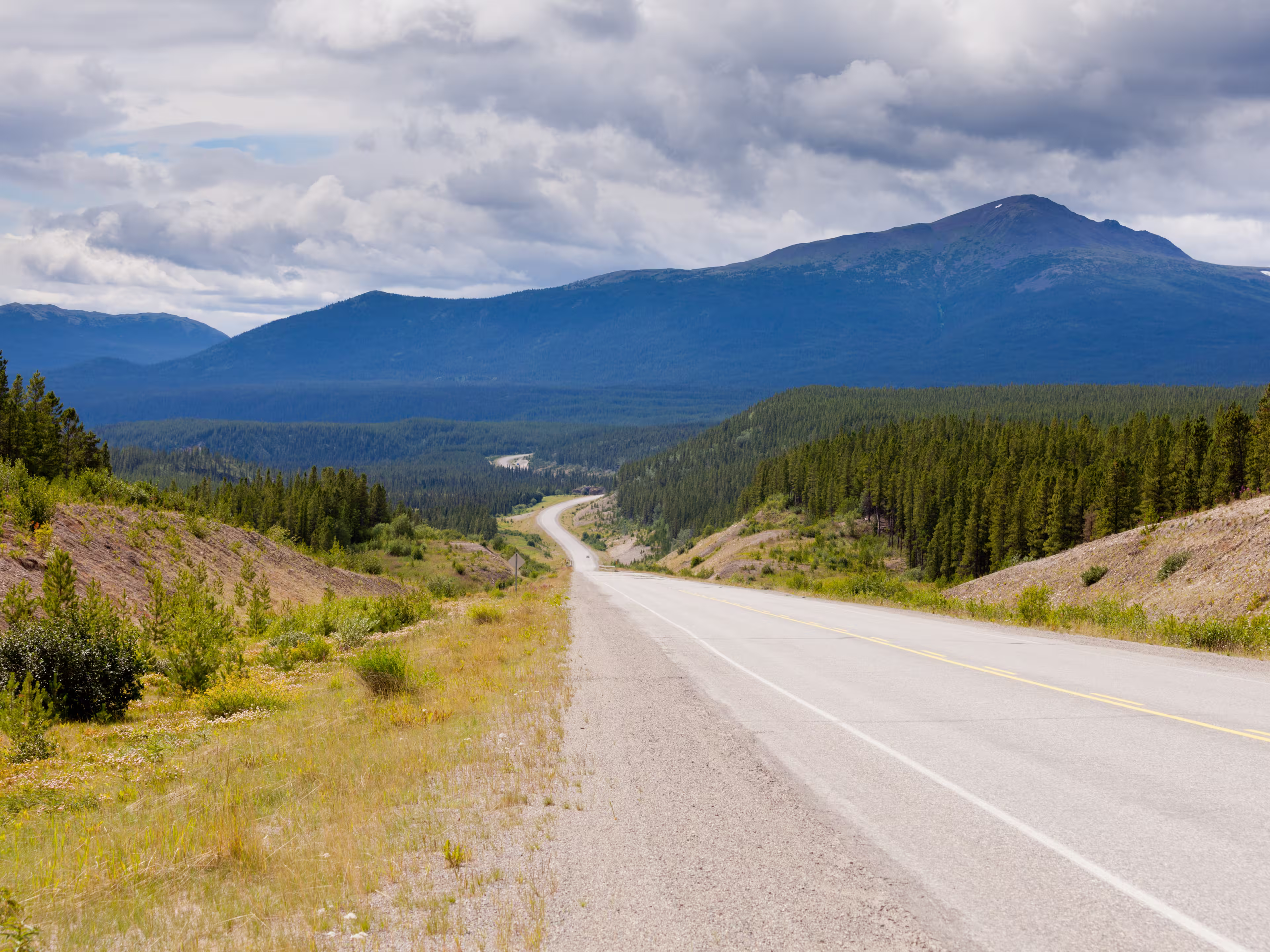 Endless empty road of Alaska Highway, Alcan, crossing wide open expanse boreal forest taiga landscape west of Watson Lake, Yukon Territory, Canada