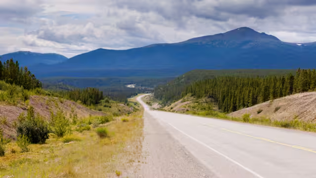 Endless empty road of Alaska Highway, Alcan, crossing wide open expanse boreal forest taiga landscape west of Watson Lake, Yukon Territory, Canada