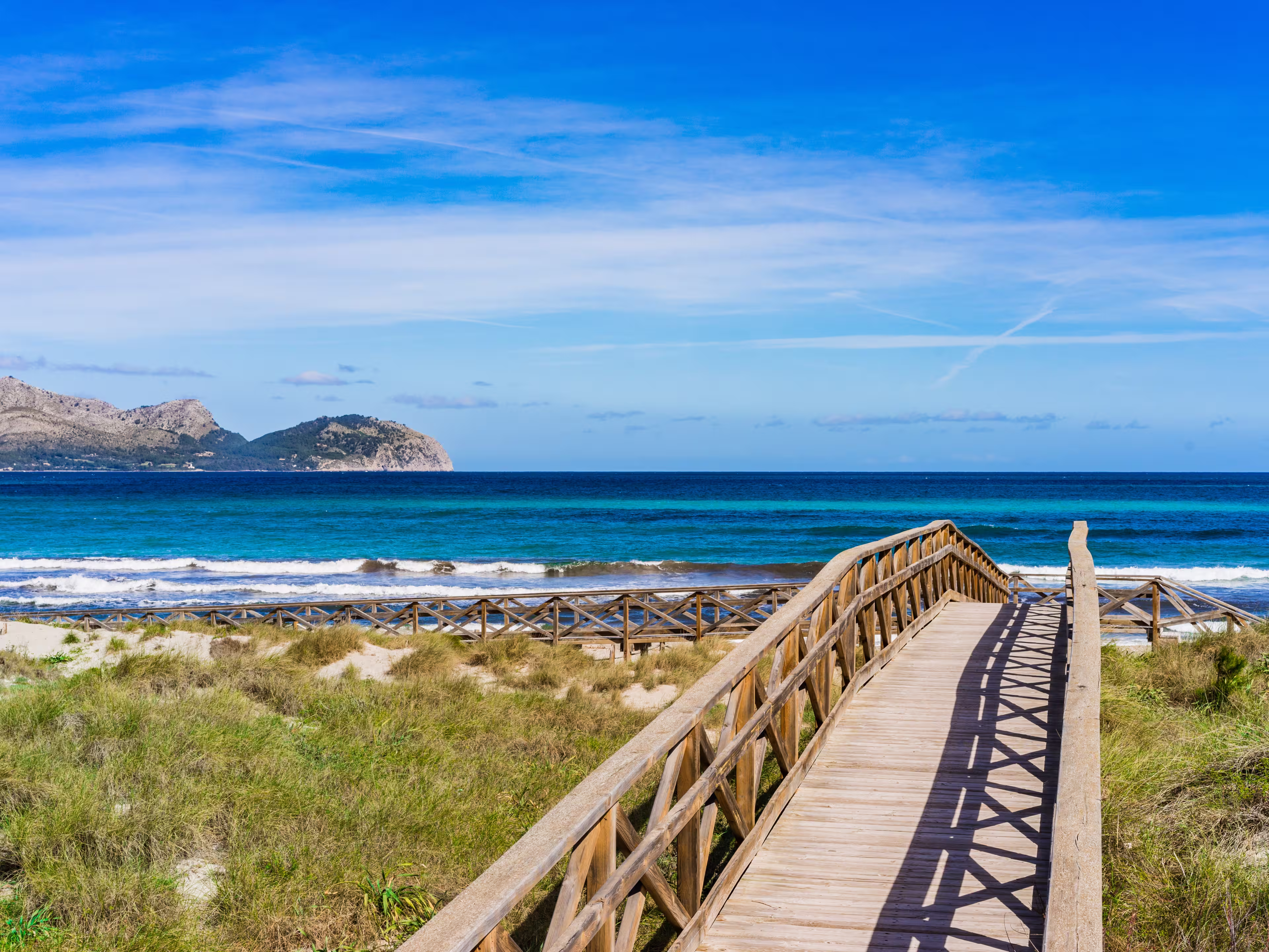 Wooden footbridge at the dunes of the sand beach in Can Picafort, Alcudia Majorca Spain, seaside Mediterranean Sea.