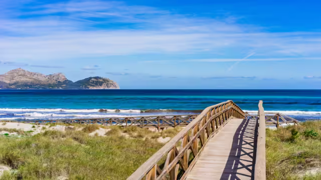Wooden footbridge at the dunes of the sand beach in Can Picafort, Alcudia Majorca Spain, seaside Mediterranean Sea.
