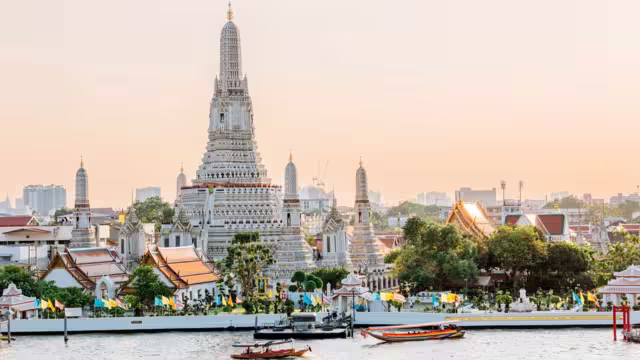 Wat Arun Temple in Bangkok with Cho Phraya river and Bangkok skyline at sunset
