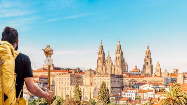Santiago de Compostela cityscape, Spain - Camino de Santiago pilgrim with yellow backpack arrives at the end of the road