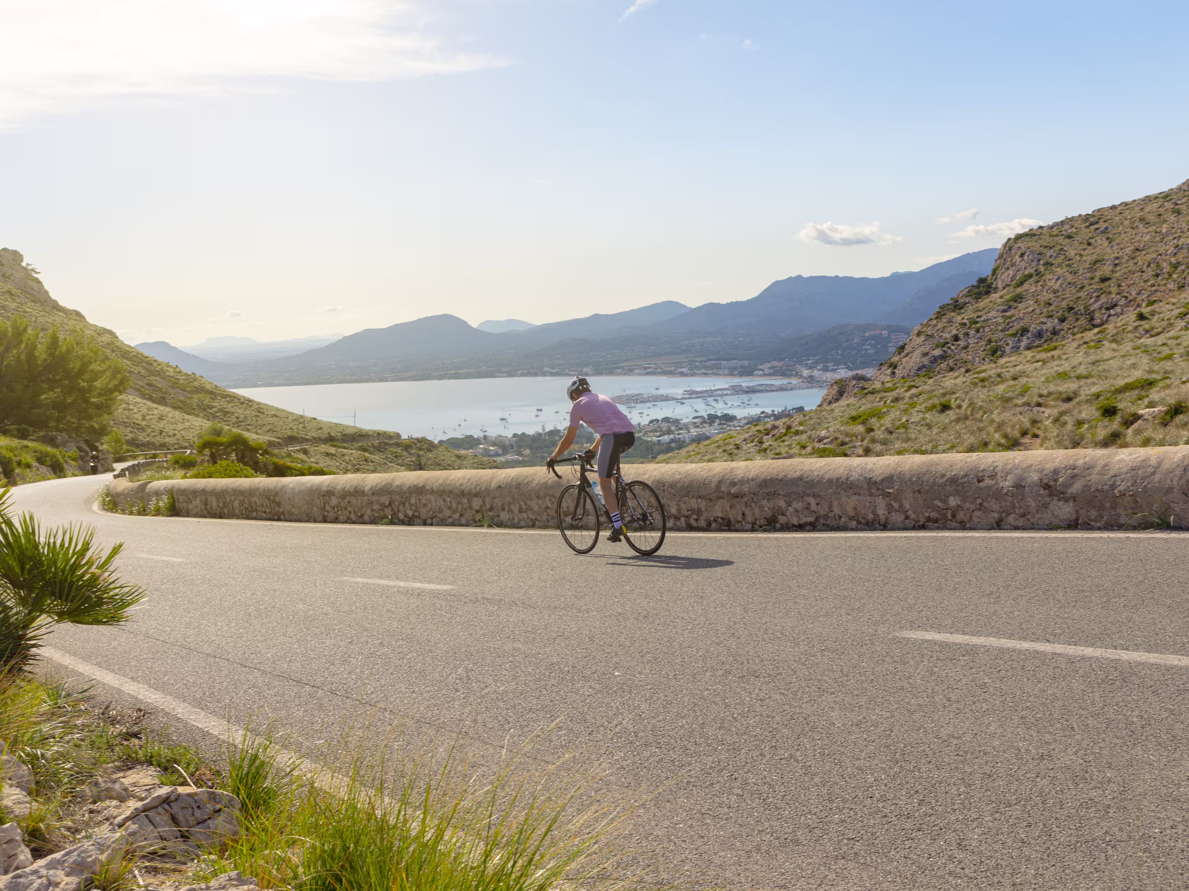 Mallorca Cycling. Cyclist descending a slope towards the port of Pollensa, near the Es Colomer viewpoint in Formentor.