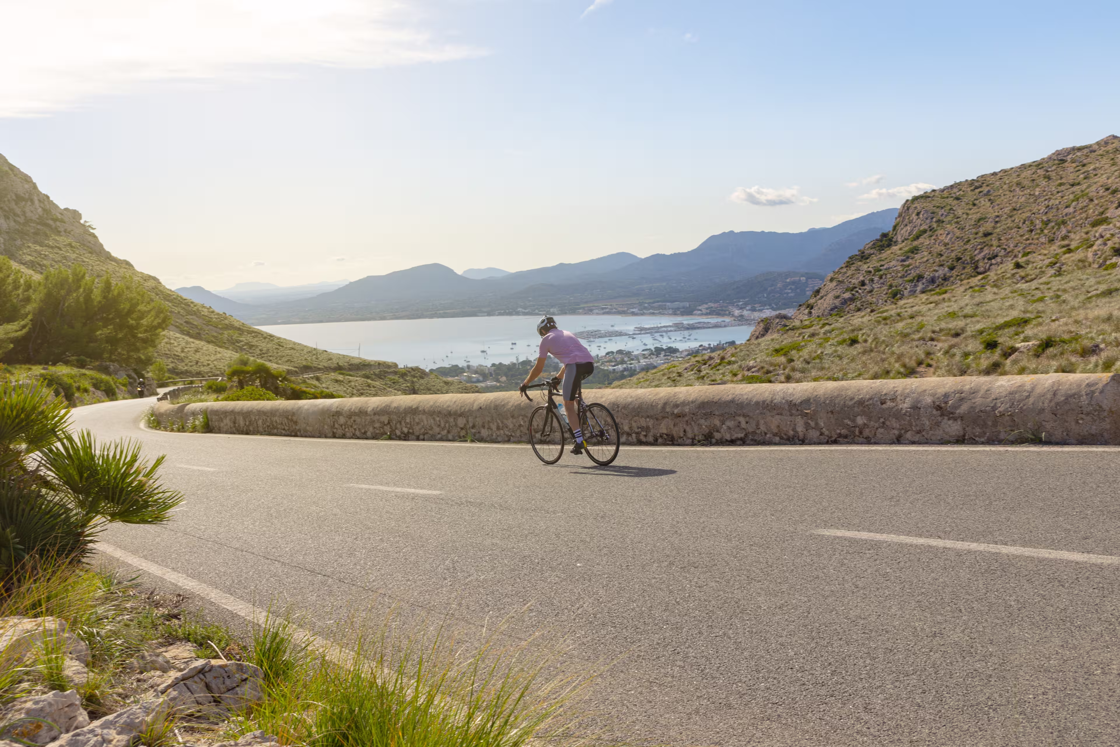 Mallorca Cycling. Cyclist descending a slope towards the port of Pollensa, near the Es Colomer viewpoint in Formentor.