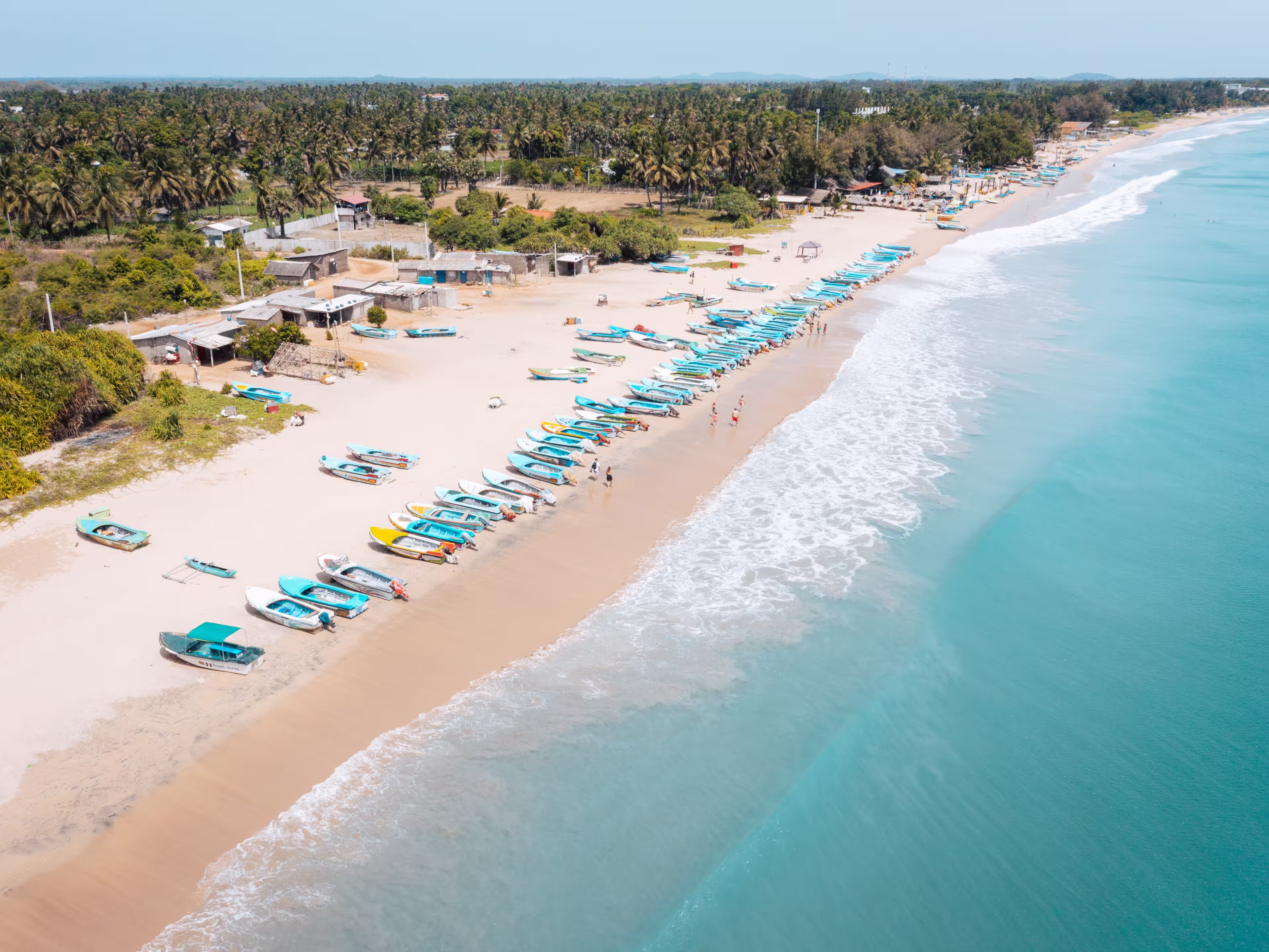 Fishing boats pulled up on sandy shoreline at Nilaveli Beach, Nilaveli, Sri Lanka, with clear turquoise water of the Indian Ocean along the tropical coast.