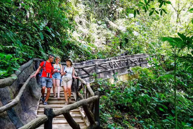 Traveller group with leader walking along bridge at La Fortuna Waterfall, Costa Rica