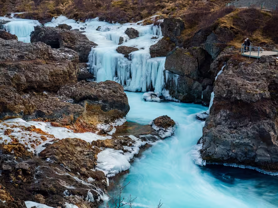 Onlookers view a frozen Barnafoss, or Children’s Falls, a waterfall in West Iceland near Husafell and the Hvita River. Flowing through a narrow rocky gorge in Borgarfjordur.