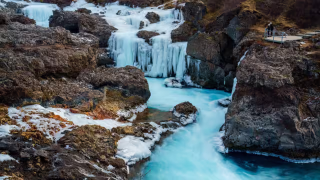 Onlookers view a frozen Barnafoss, or Children’s Falls, a waterfall in West Iceland near Husafell and the Hvita River. Flowing through a narrow rocky gorge in Borgarfjordur.