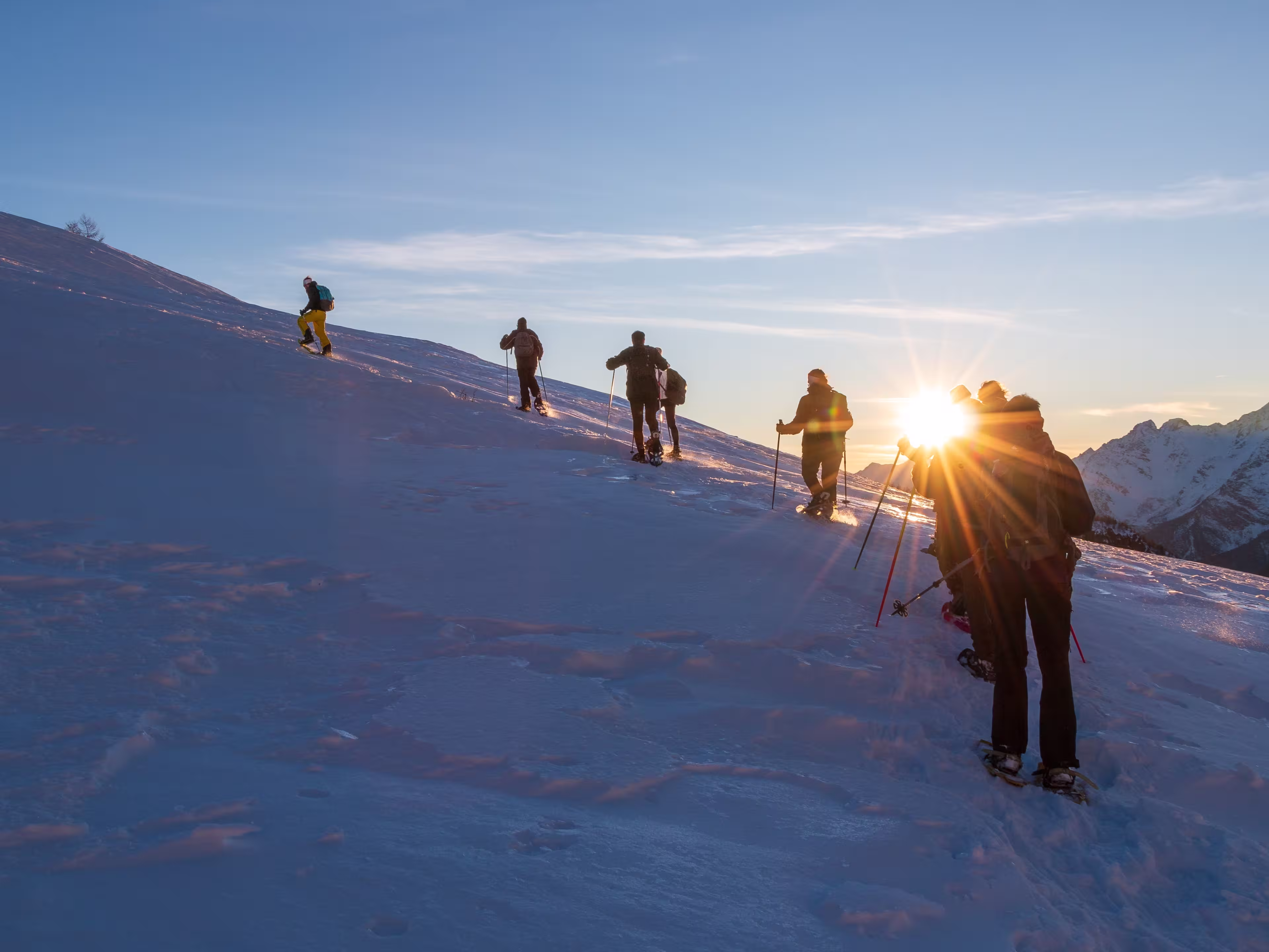 the group of snowshoes faces the climb up the snowy side of the mountain