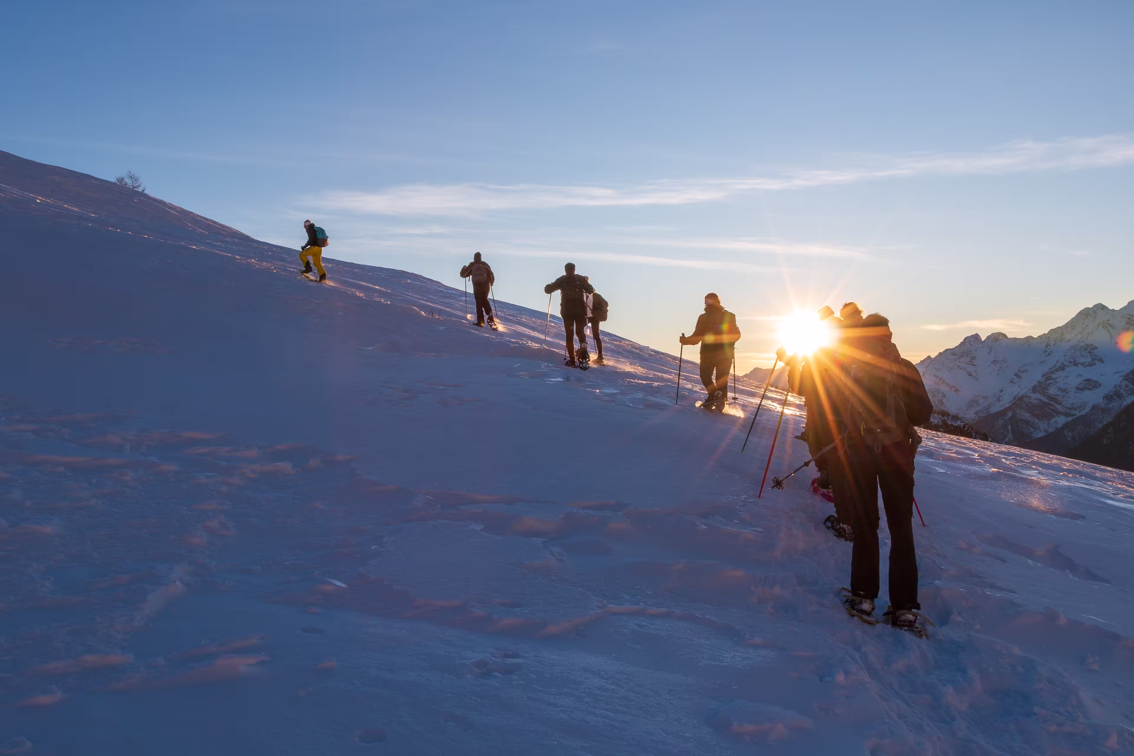 the group of snowshoes faces the climb up the snowy side of the mountain