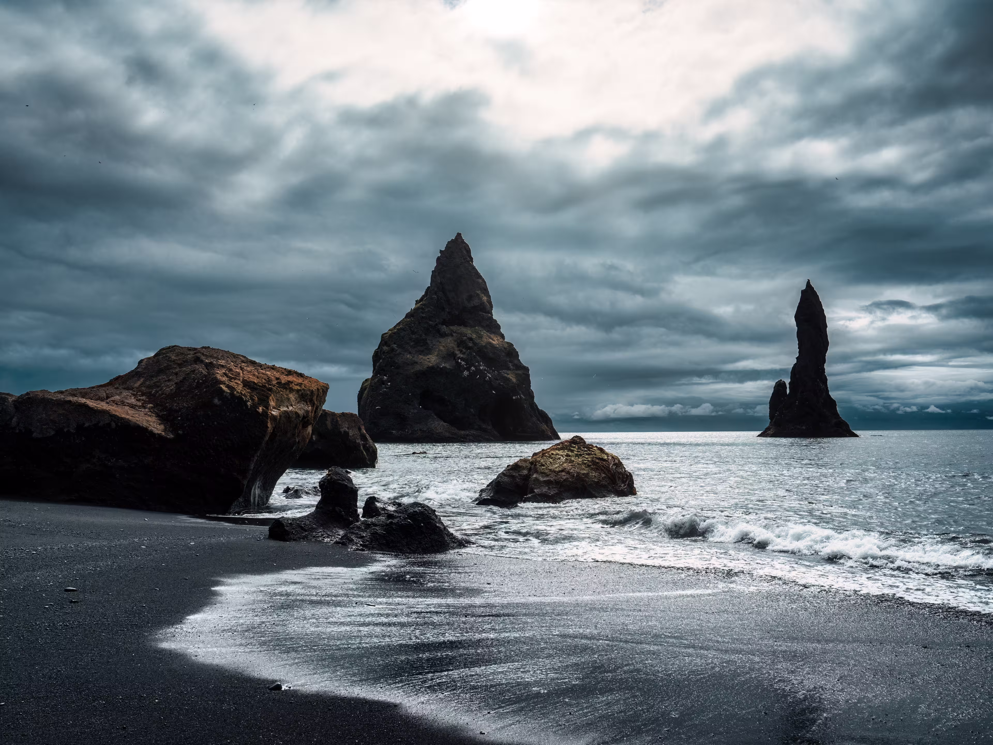 Dramatic landscape of moody Reynisdragar natural rock formation on Reynisfjara black sand beach in Atlantic ocean at Vik, South of Iceland