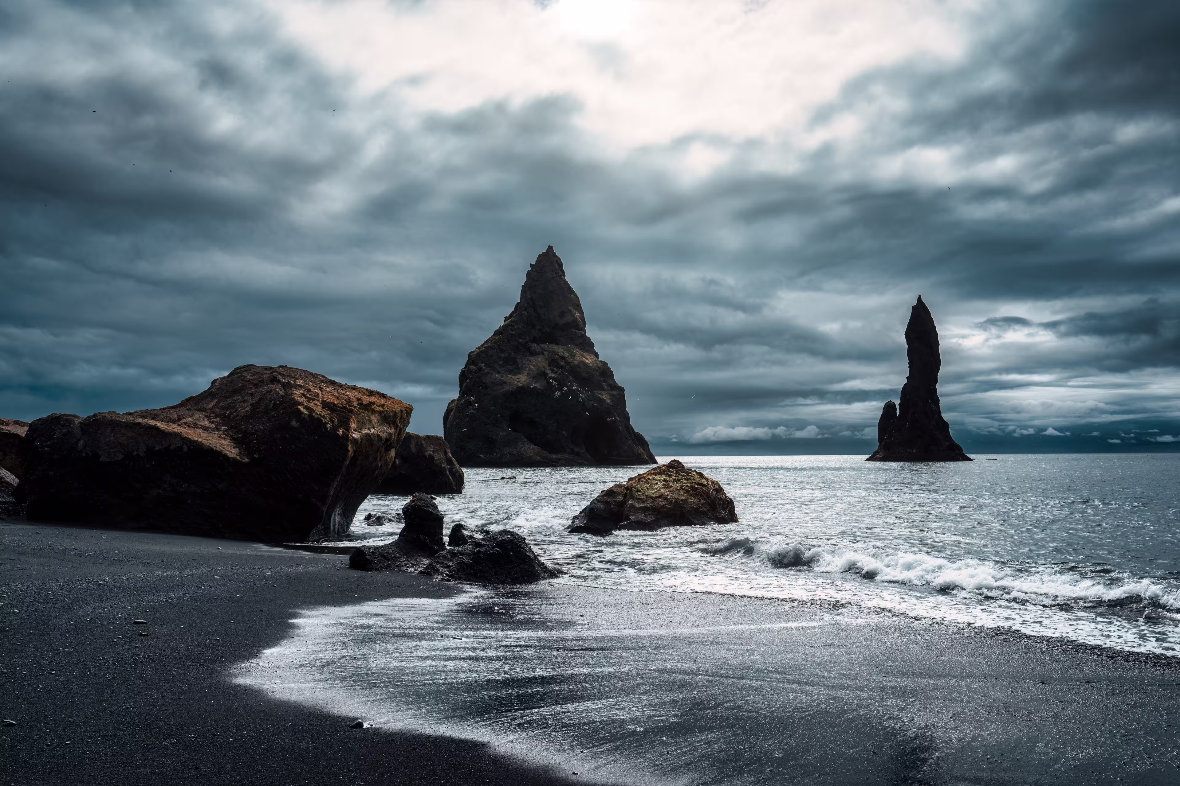 Dramatic landscape of moody Reynisdragar natural rock formation on Reynisfjara black sand beach in Atlantic ocean at Vik, South of Iceland