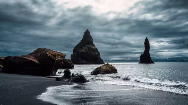 Dramatic landscape of moody Reynisdragar natural rock formation on Reynisfjara black sand beach in Atlantic ocean at Vik, South of Iceland