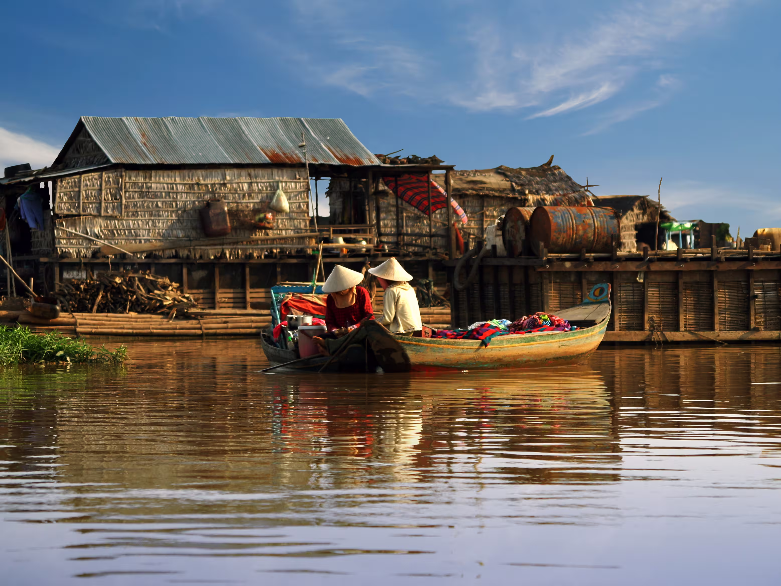 Cambodian women sail on a boat near the fishing village of Tonle Sap Lake