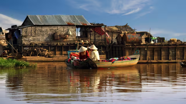 Cambodian women sail on a boat near the fishing village of Tonle Sap Lake