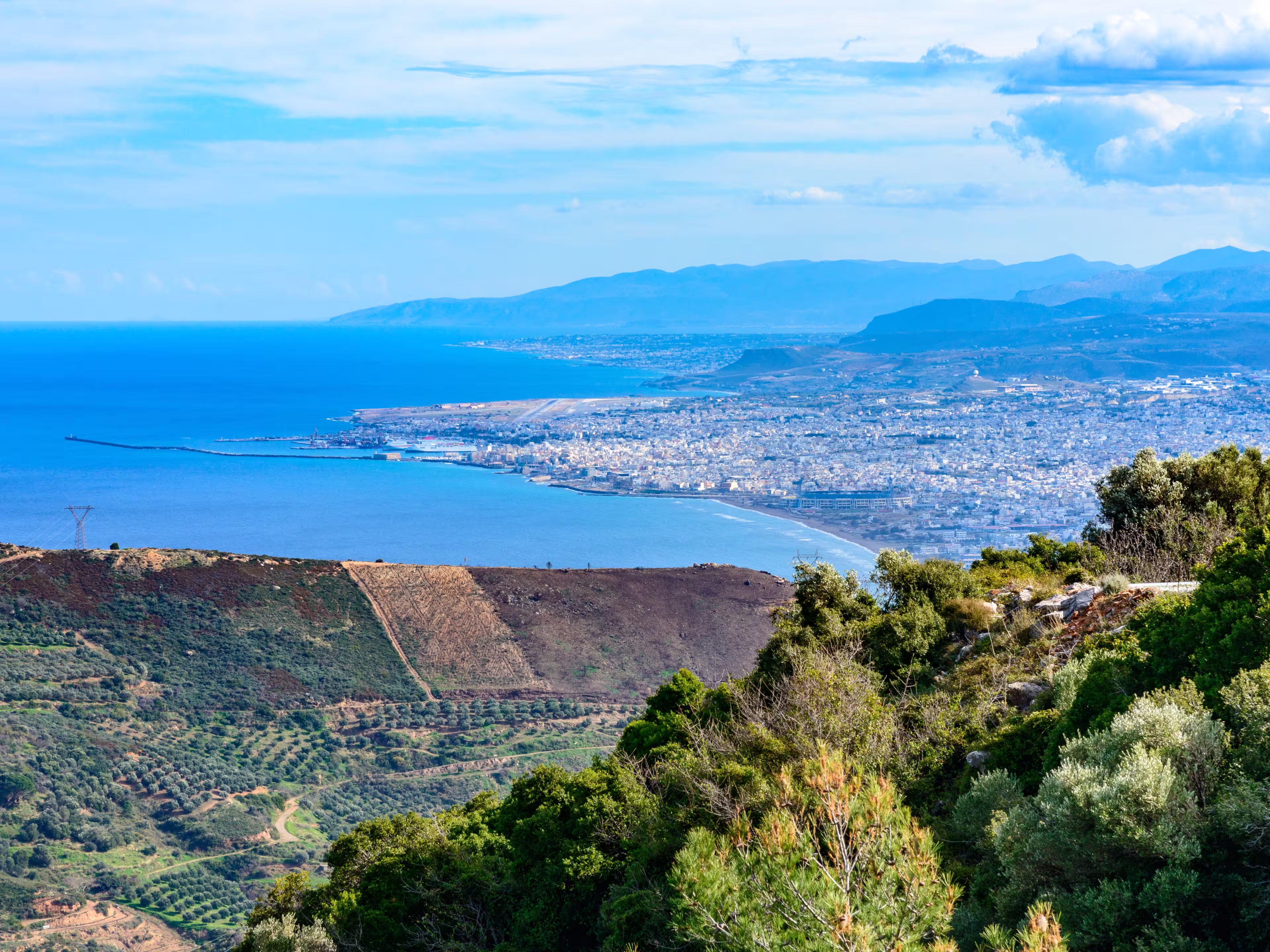 Panoramic skyline view of Mediterranean vacation destination Heraklion city, airport, popular resorts  Ammoudara,  Kokkini Hani, Gouves, Analipsi, and Lasithi mountains in background. Crete Greece.