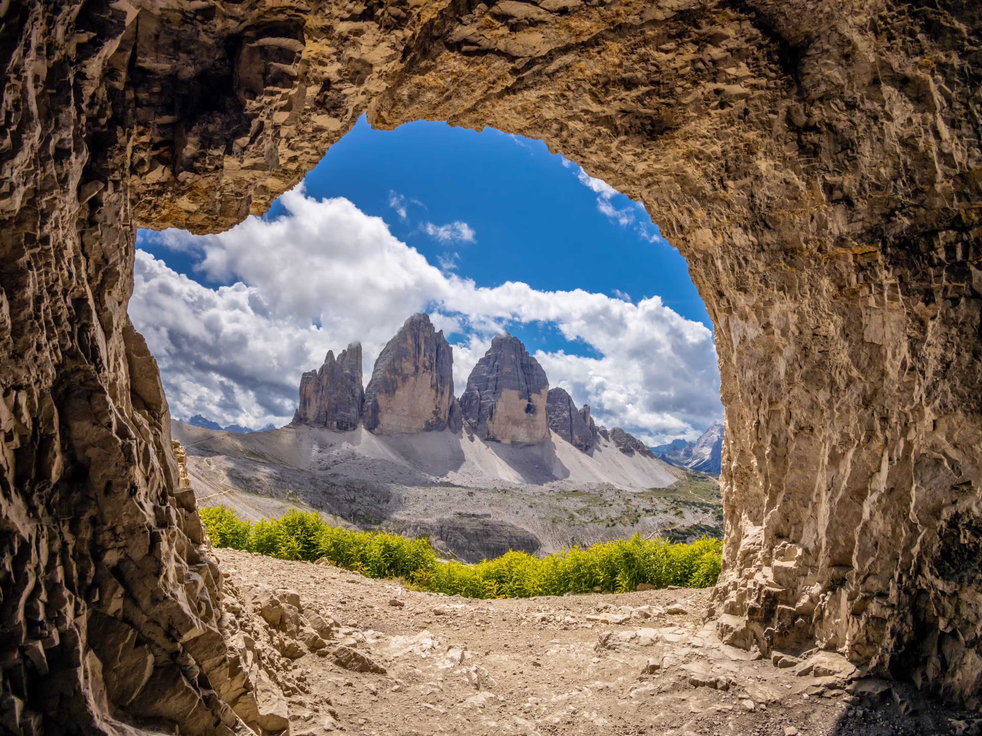 Tre Cime di Lavaredo, Drei Zinnen three peaks towers the symbol of the Dolomites. Beautiful mountain peaks towering above the valley in Dolomiti Alps with some clouds around the summit