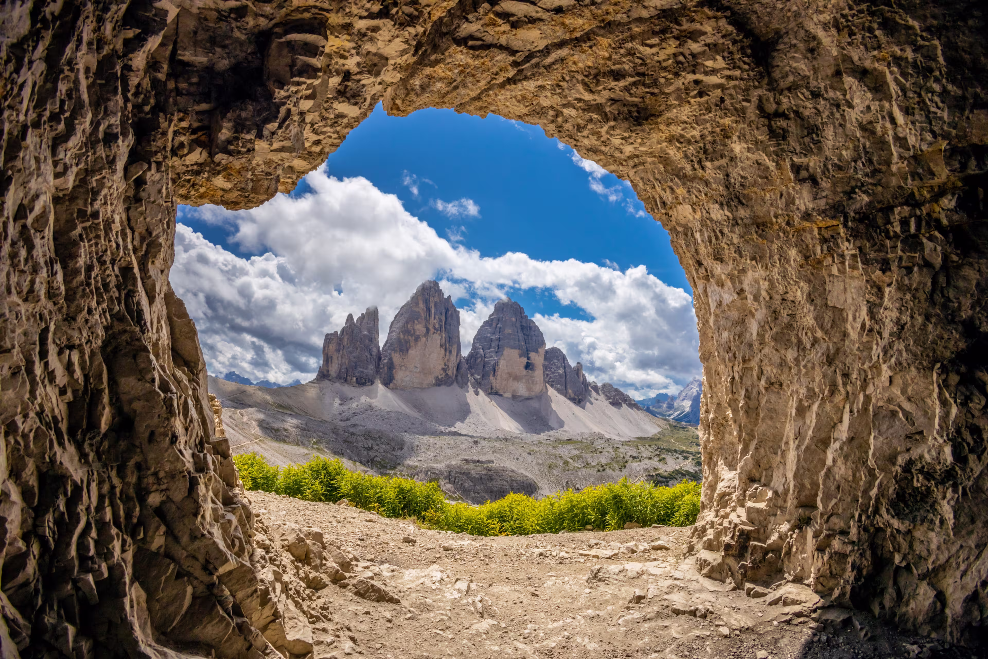 Tre Cime di Lavaredo, Drei Zinnen three peaks towers the symbol of the Dolomites. Beautiful mountain peaks towering above the valley in Dolomiti Alps with some clouds around the summit