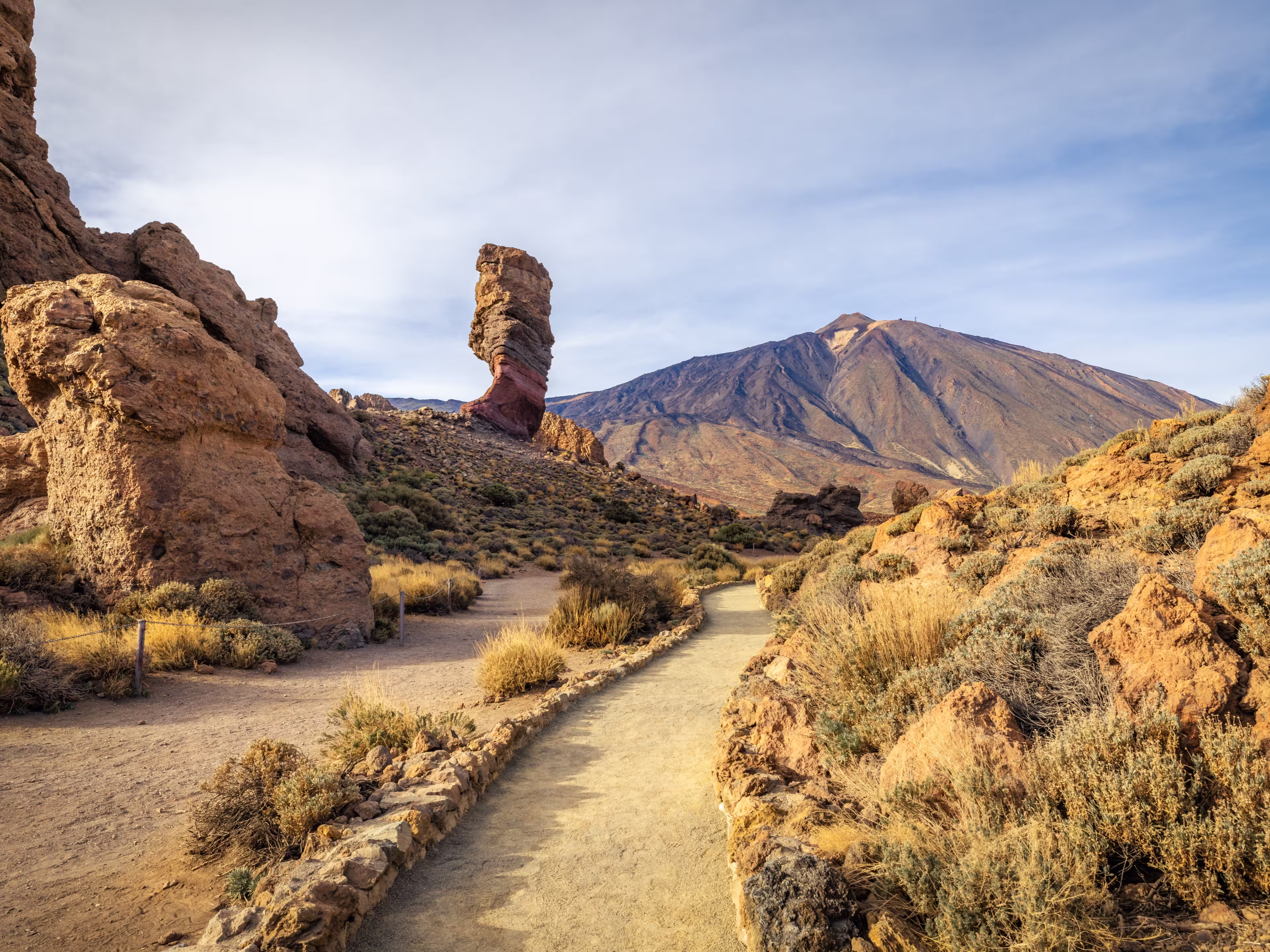 Panoramic view of Roque Cinchado, an unique rock formation with famous Pico del Teide mountain volcano summit in the background on a sunny day, Teide National Park, Tenerife, Canary Islands, Spain
